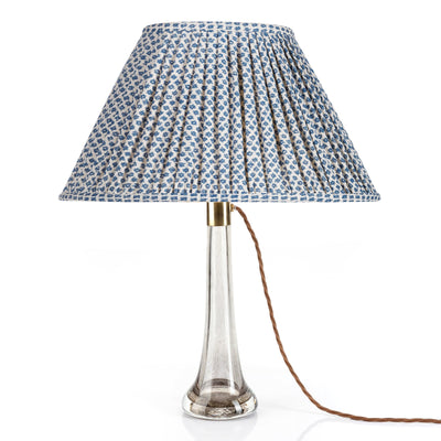 Front view of Fermoie Blue Marden oval lampshade, featuring a luxury gathered empire style with a blue floral pattern, displayed on a clear glass lamp base.