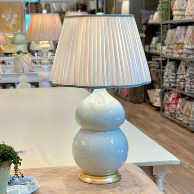 Hwang Bishop Nanjing lamp in sky blue with a scalloped white pleated lampshade with light blue trim.